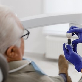 Dentist showing patient a model of the three parts of a dental implant