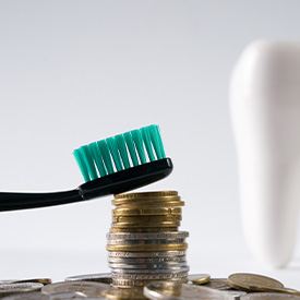 A toothbrush resting on a stack of coins, a tooth blurred in the background