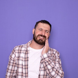 man standing against purple background, experiencing dental pain