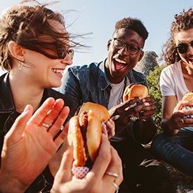 Diverse group of young adults smiling and eating hamburgers together