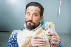 Man looking at model dental implants with raised eyebrow
